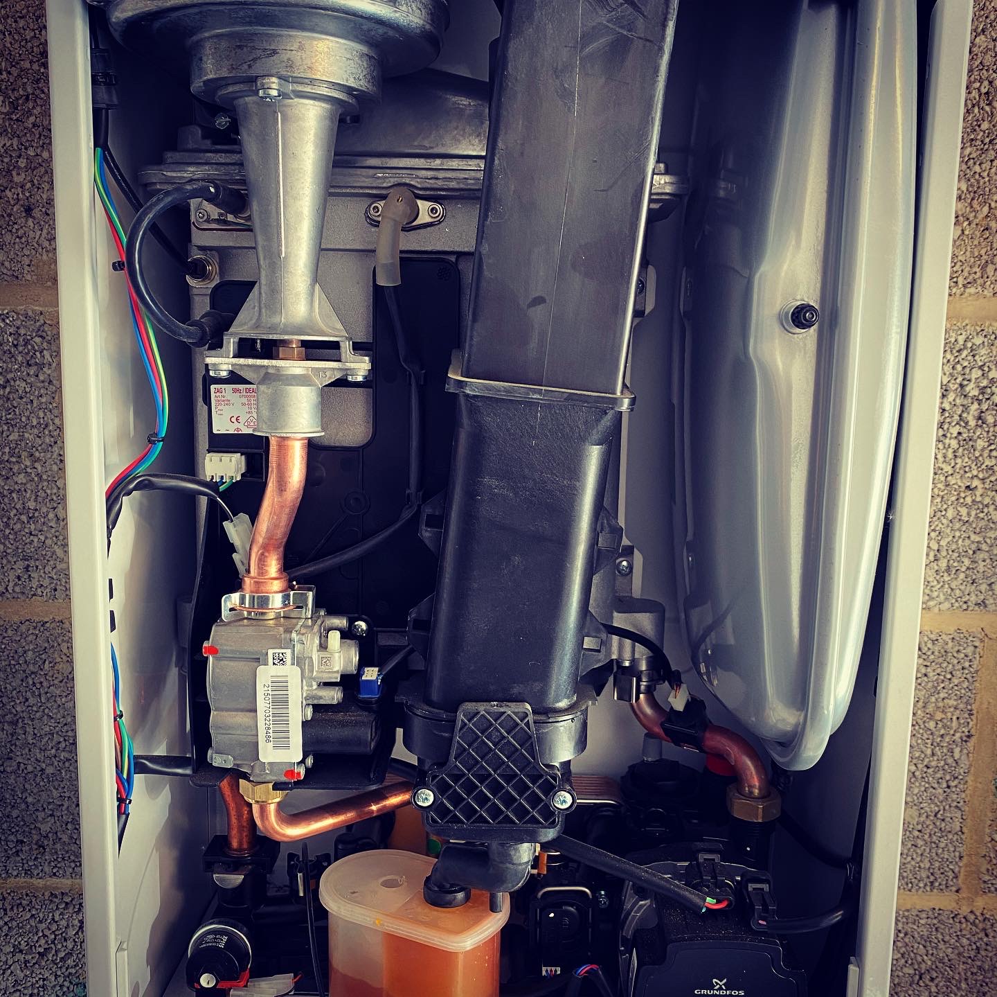 Inside a boiler during a service: gas valve, burner and copper pipework